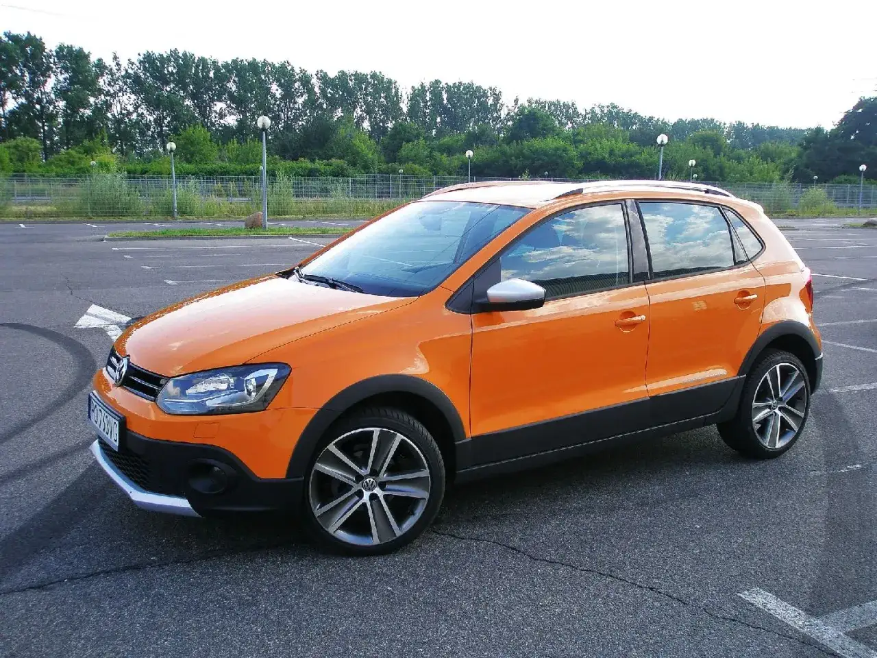 Pomarańczowy Volkswagen Polo Cross stoi na pustym parkingu.