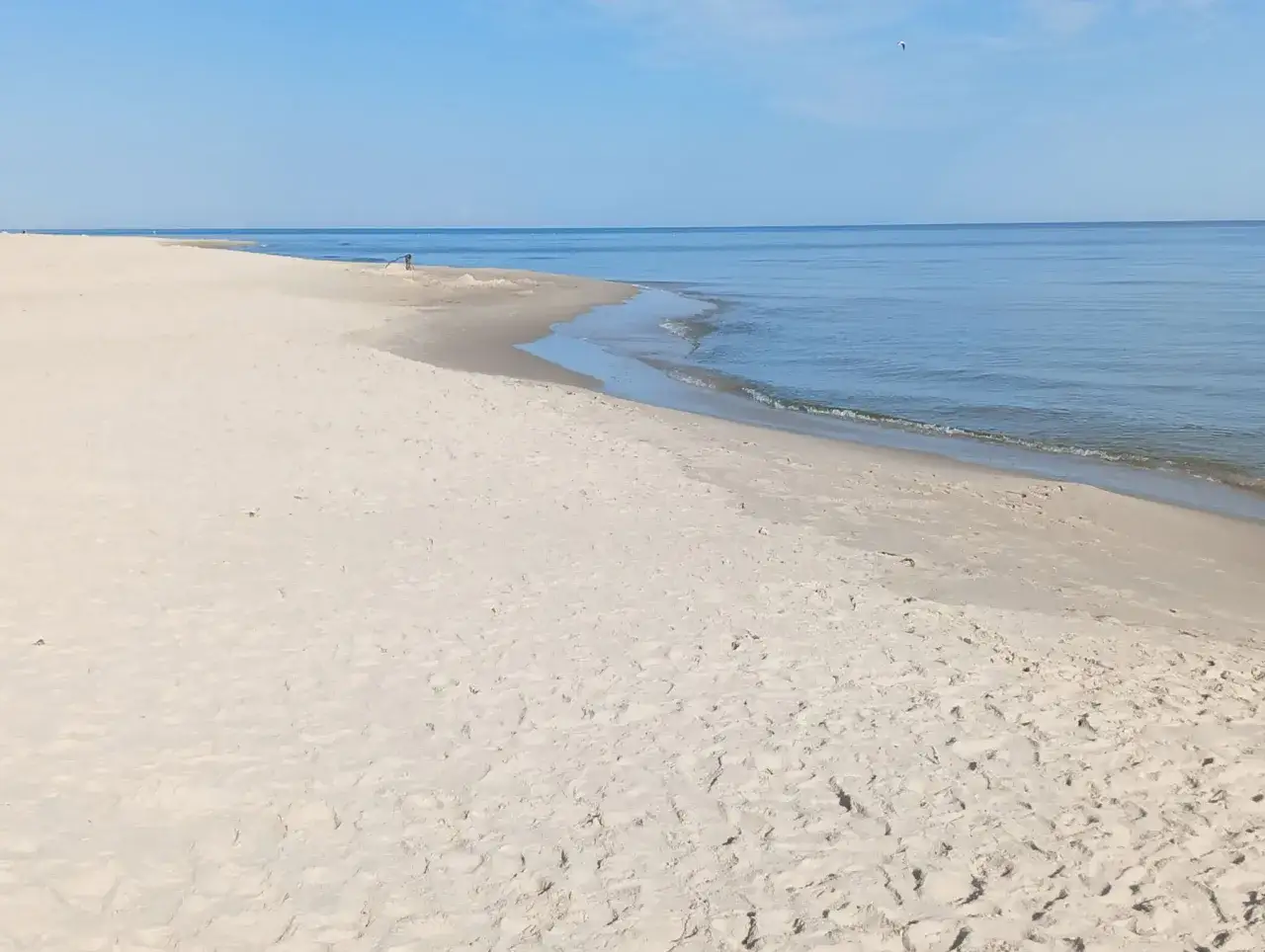Pusta, piaszczysta plaża nad spokojnym morzem. Idealne miejsce na relaks i odkrywanie **karwia atrakcje w okolicy**.