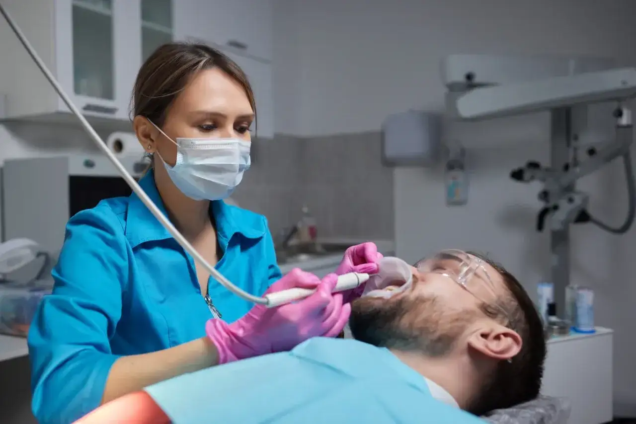 Dentystka usuwa kamień na zębach pacjentowi.