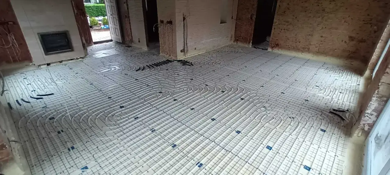 Installation d'un plancher chauffant avant le d&eacute;sembouage. Les tuyaux sont pos&eacute;s en spirale sur une grille.