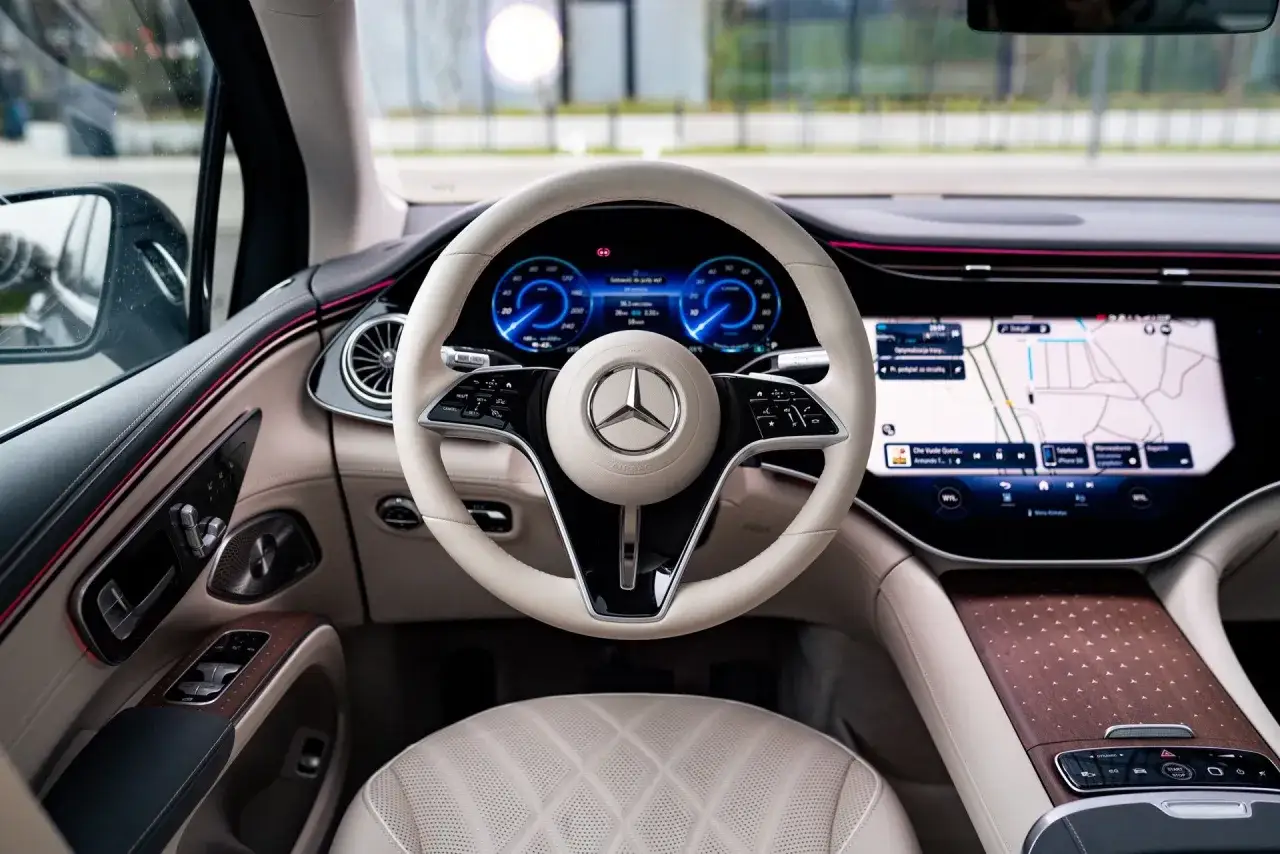 Wnętrze luksusowego **Mercedes EQS SUV** z jasną tapicerką, nowoczesnym kokpitem i ekranem nawigacji.