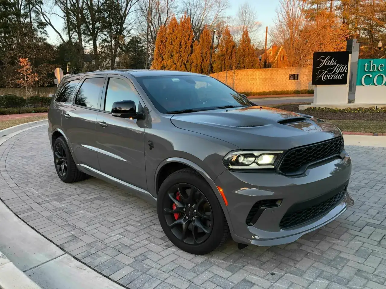 Szary Dodge Durango SRT Hellcat z czarnymi felgami i czerwonymi zaciskami hamulcowymi stoi na brukowanym podjeździe.