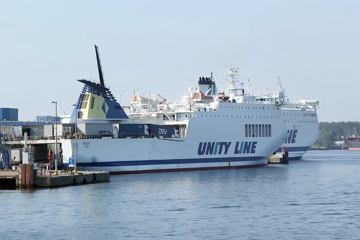 Dwa białe promy Unity Line cumują w porcie. Na jednym z nich widać ciężarówki.