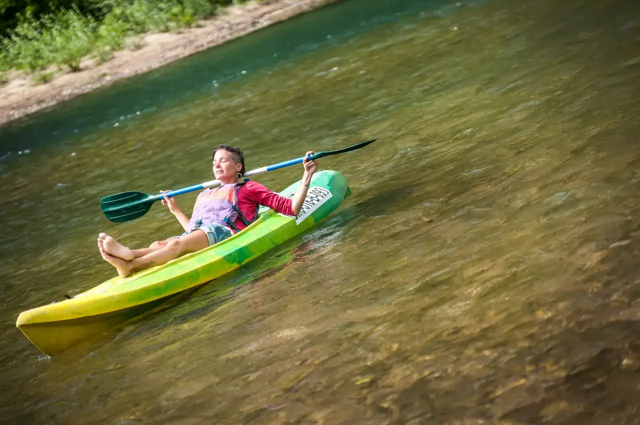 Persona relajada en kayak durante un tren descenso del Sella, disfrutando del sol y el agua.