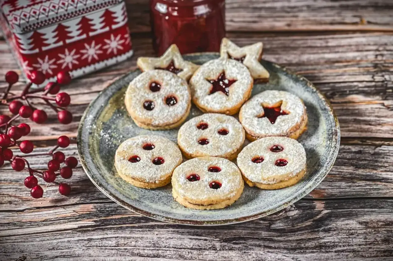 Ein Teller mit **die besten spitzbuben der welt**, best&auml;ubt mit Puderzucker, daneben ein Glas Marmelade und ein Weihnachtsblech.