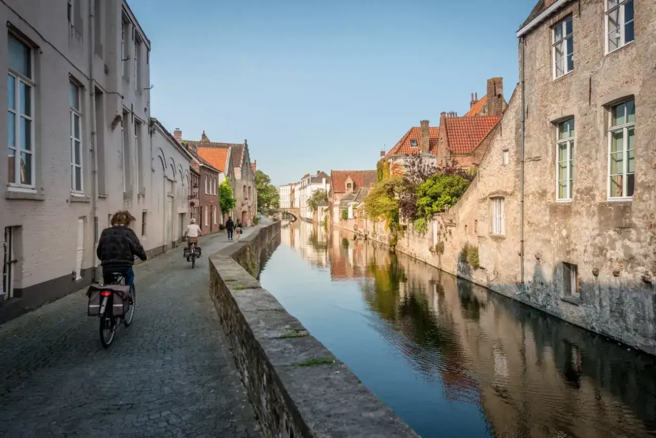 Enjoying a peaceful Bruges bike tour along a canal, with historic buildings reflecting in the water.