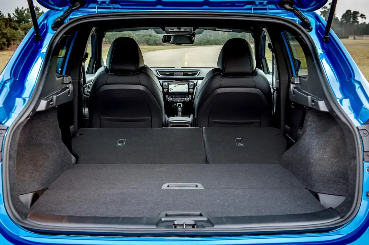 Insidan av en blå Nissan Qashqai, med öppen baklucka. Framstolarna och instrumentpanelen syns. Perfekt för ett nissan qashqai test.