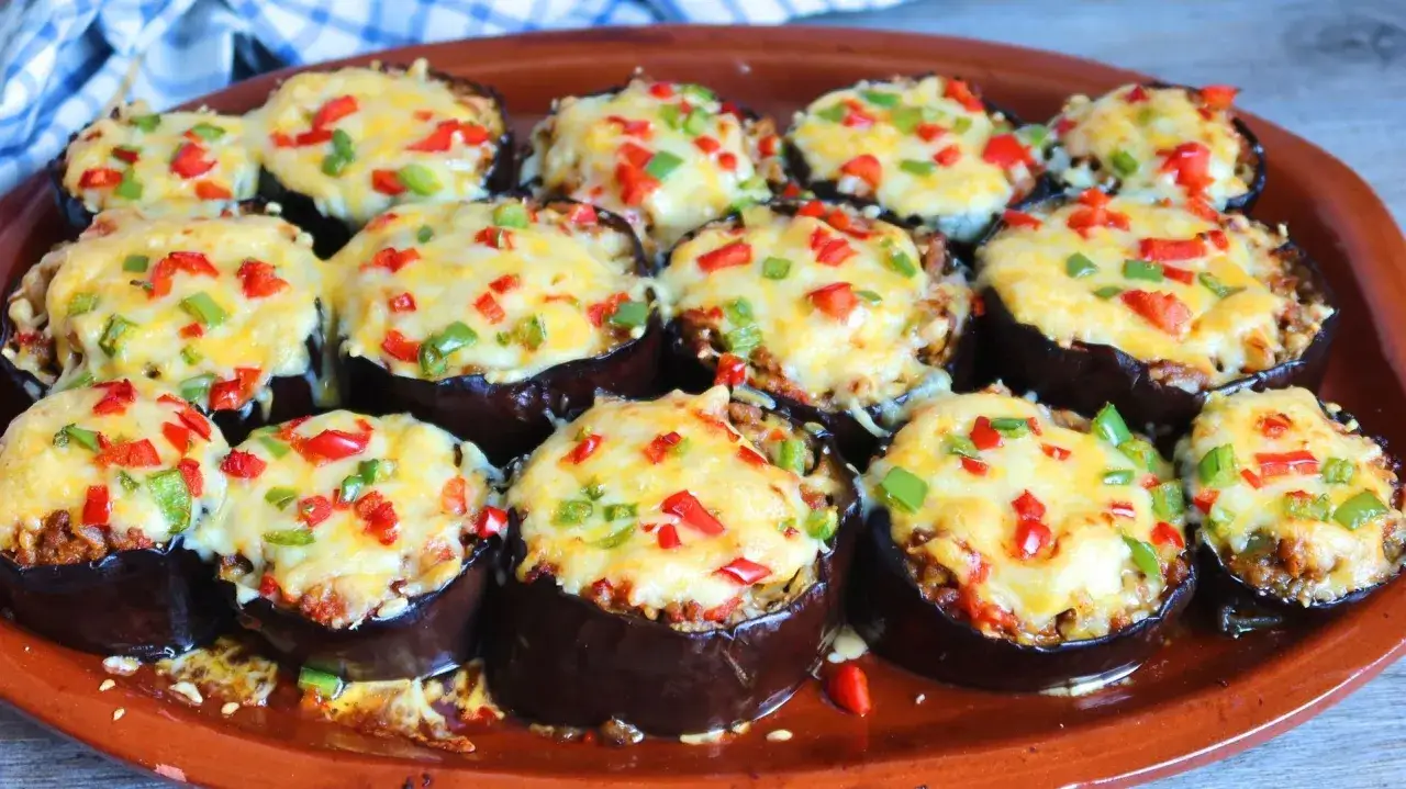 Berenjenas rellenas de carne picada, cubiertas de queso fundido y pimientos rojos y verdes. ¡Un plato delicioso y casero!