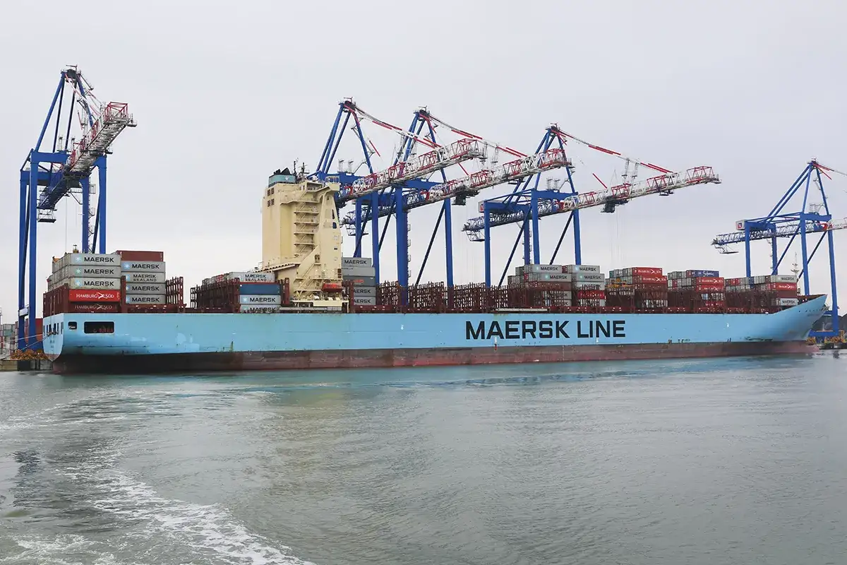 Ogromny kontenerowiec Maersk Line z milionami kontenerów na pokładzie, zacumowany w porcie pod wielkimi dźwigami.