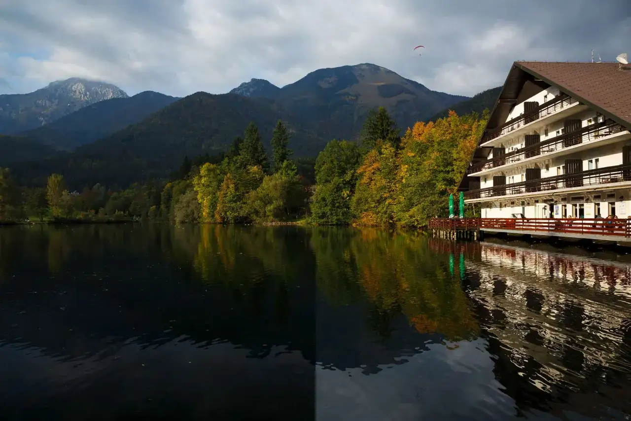 Paysage de montagne avec un lac et un h&ocirc;tel, un parapente dans le ciel. L'effet du filtre polarisant photo rend l'eau plus sombre et les couleurs plus vives.