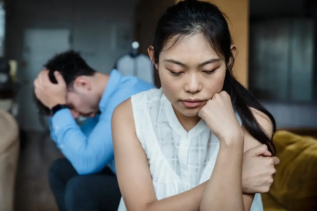 Una donna pensierosa e un uomo disperato, seduti schiena contro schiena. Un momento di silenzio, quando non si ama più il proprio marito.