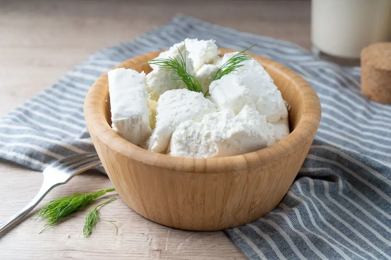 Twaróg w drewnianej misce, udekorowany koperkiem. Czy twaróg jest zdrowy? Tak, to pyszny i wartościowy produkt.