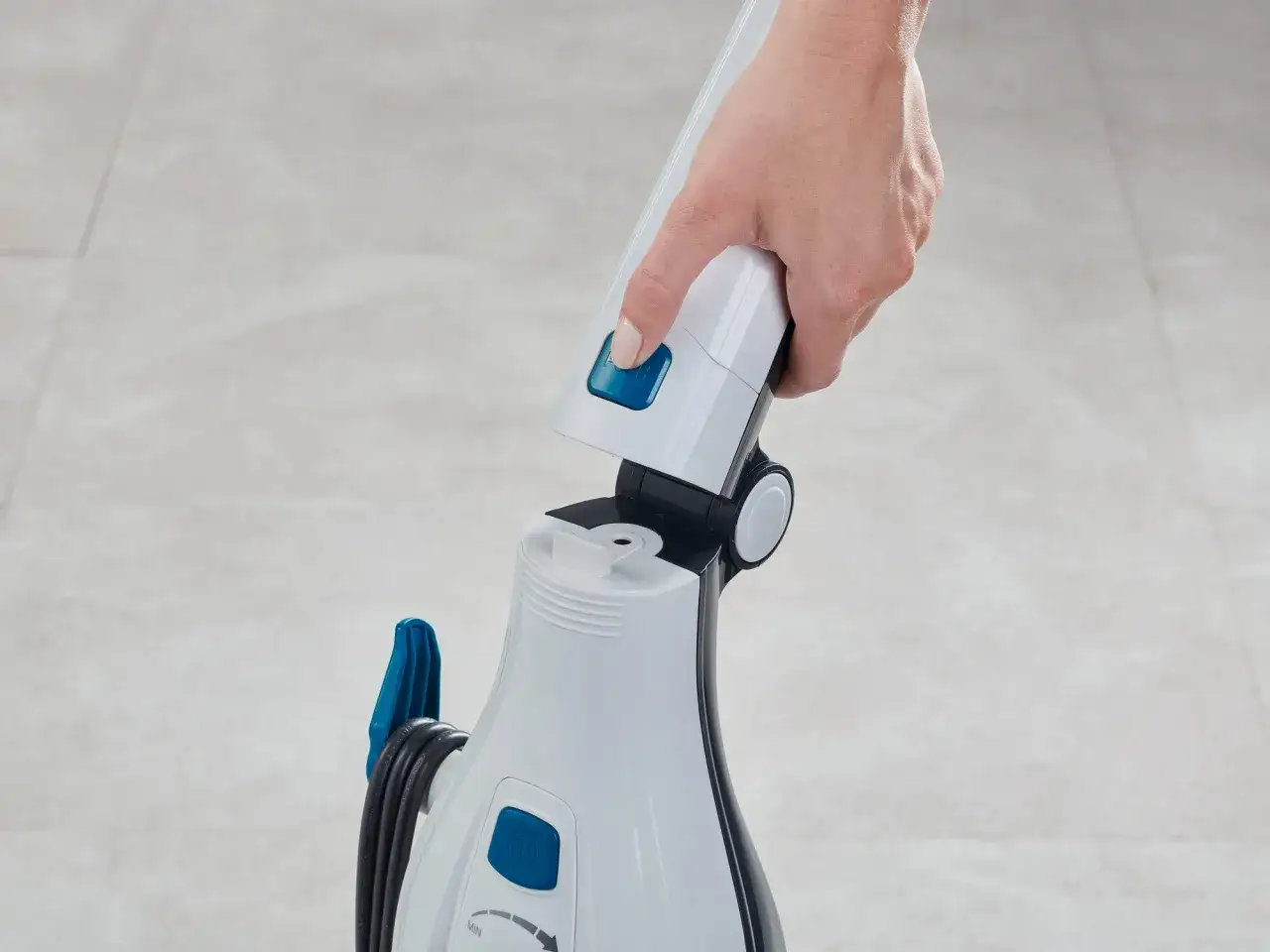 Hand connects handle to a white steam cleaner, ready for cleaning laminate floors.
