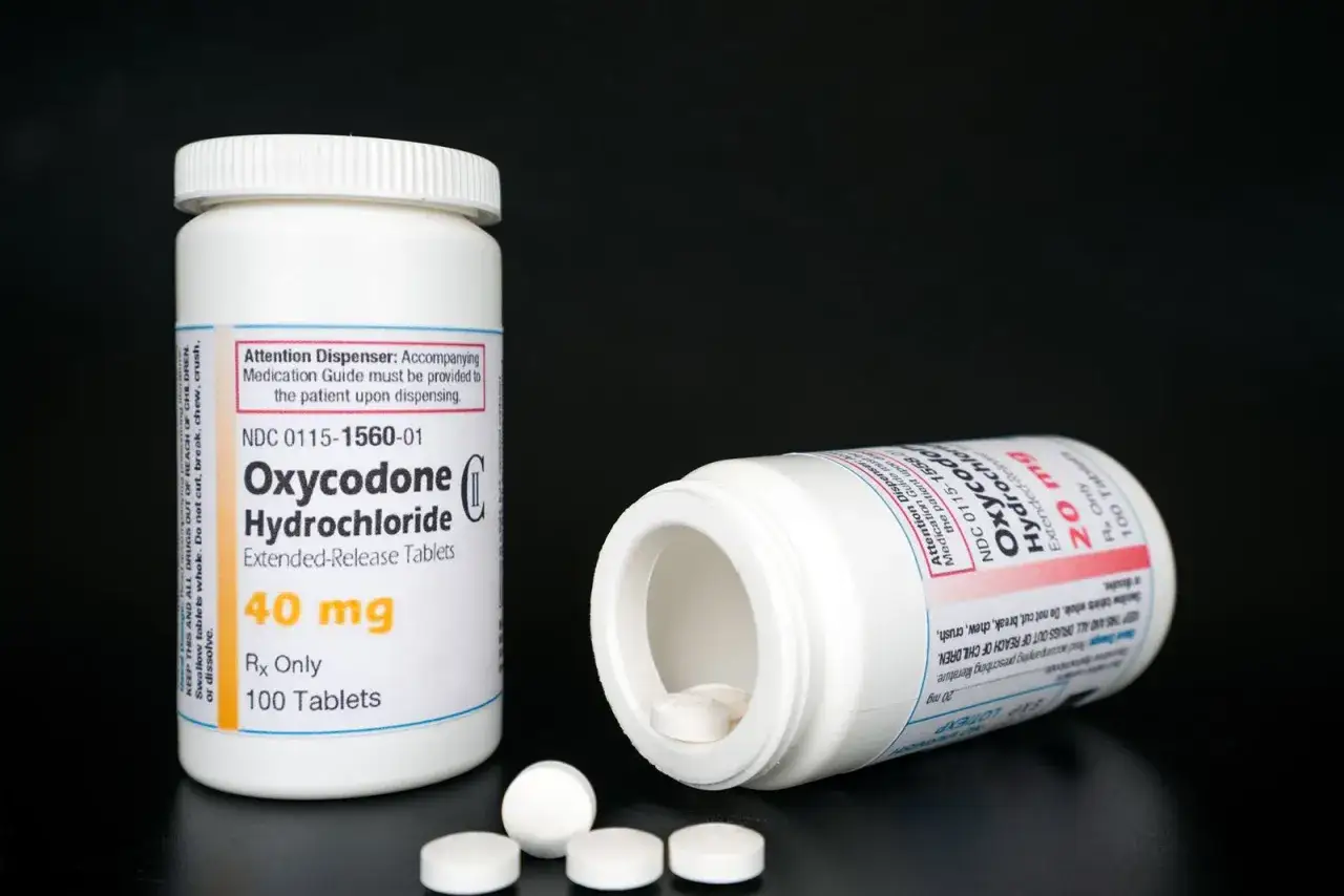 Dwie butelki tabletek Oxycontin 40 mg i 20 mg, jedna otwarta z tabletkami na zewnątrz.