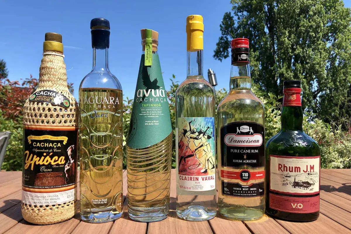 Różne butelki cachaca i rumu na drewnianym stole. Cachaca to brazylijski destylat z trzciny cukrowej.