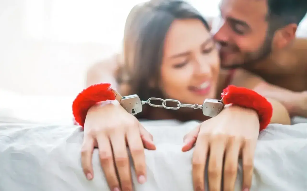 Para zmysłów w objęciach, z rękami spiętymi futrzanymi kajdankami, czerpiąca radość z praktyk BDSM.