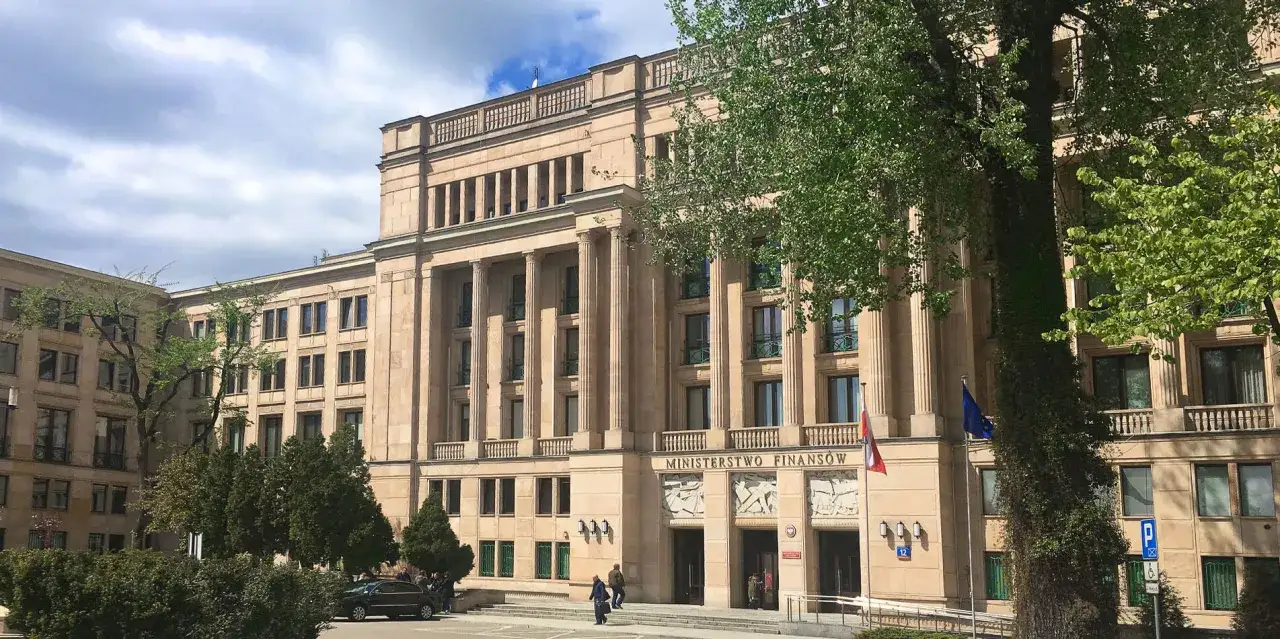 Imponujący budynek Ministerstwa Finansów z kolumnami i polską flagą.
