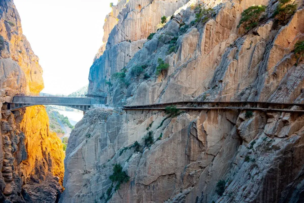 En dramatisk caminito del rey vandring l&auml;ngs en klippv&auml;gg med en bro som sp&auml;nner &ouml;ver en ravin.