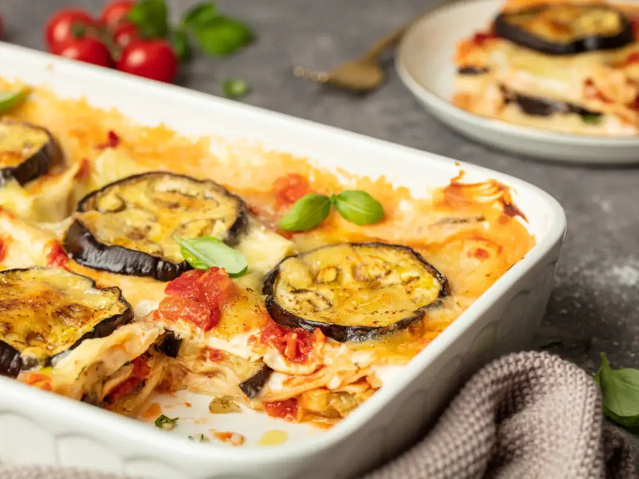 Herzhafte Auberginen Lasagne mit geschmolzenem K&auml;se und frischem Basilikum in einer Auflaufform.