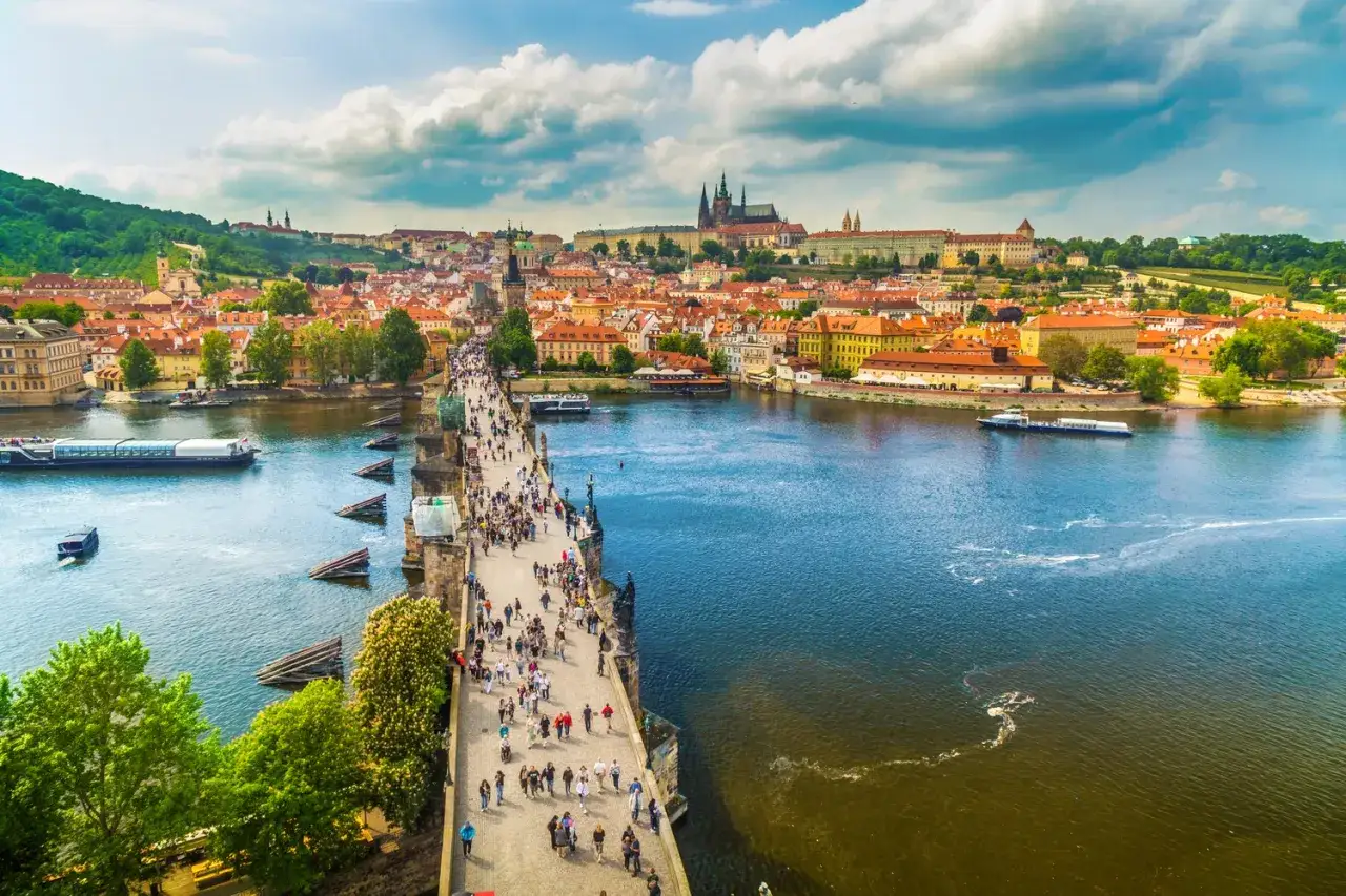 Menschen spazieren über die Karlsbrücke in Prag. Ein toller Ort, um zu sehen, was man in Prag machen kann: die Aussicht genießen, Boote auf der Moldau beobachten und die historische Stadt erkunden.