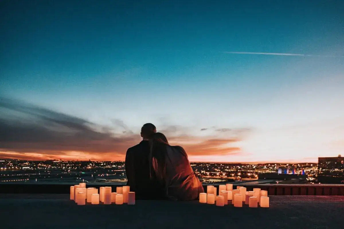Para romantyczny wieczór, idealny pomysł na pierwszą randkę: para siedzi przy świecach, patrząc na miasto nocą.