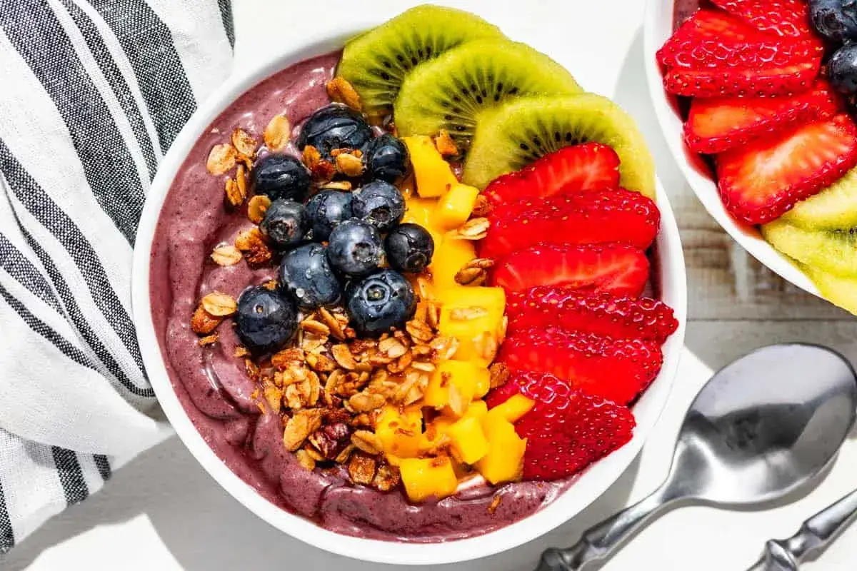 Acai-Bowl mit Blaubeeren, Erdbeeren, Kiwi und Mango. Ein vitamin-C-reicher Genuss, garniert mit Granola.