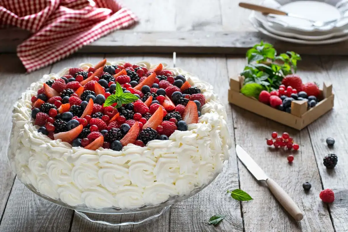 Torta con panna montata e frutti di bosco, perfetta per chi vuole imparare come si fa la crema chantilly.
