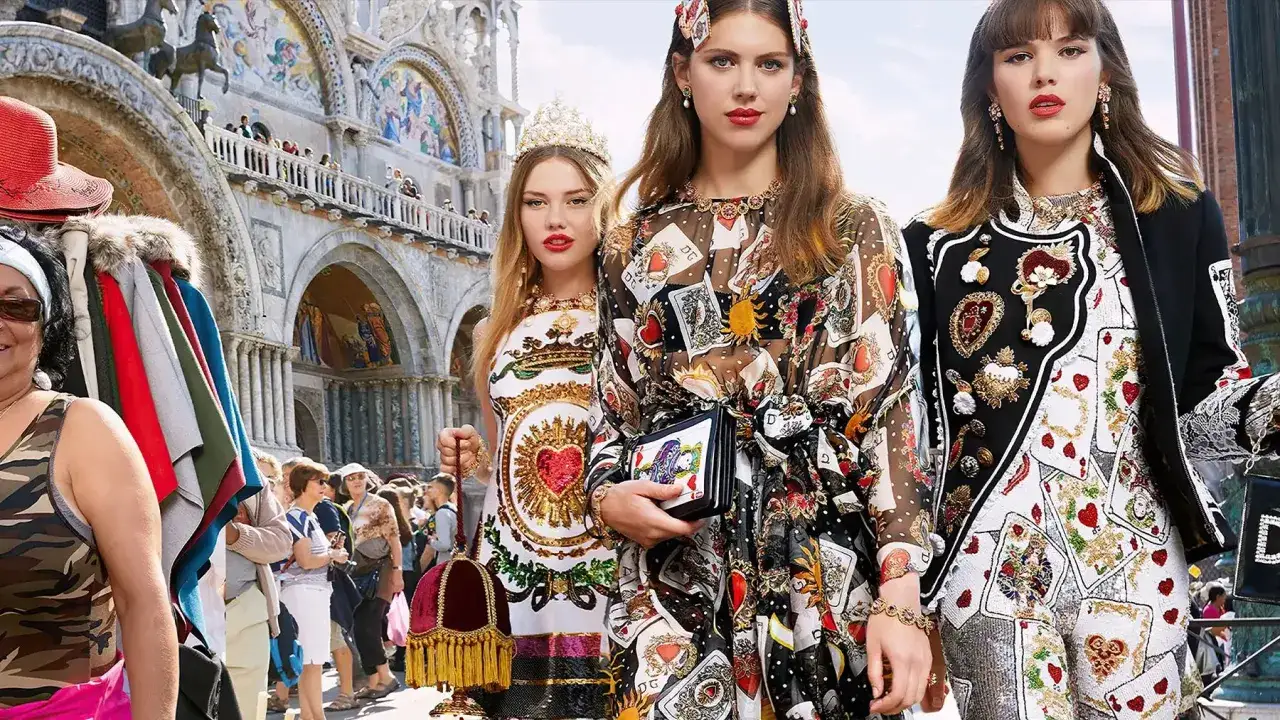 Tres mujeres con atuendos llamativos y joyas, evocando un estilo mob wife, posan frente a una basílica.