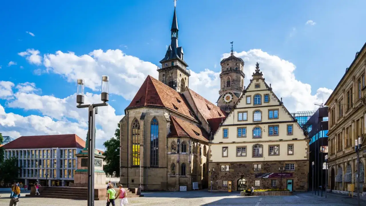 Blick auf die Stiftskirche und historische Gebäude in der Stuttgarter Innenstadt. Ein sonniger Tag mit Wolken.
