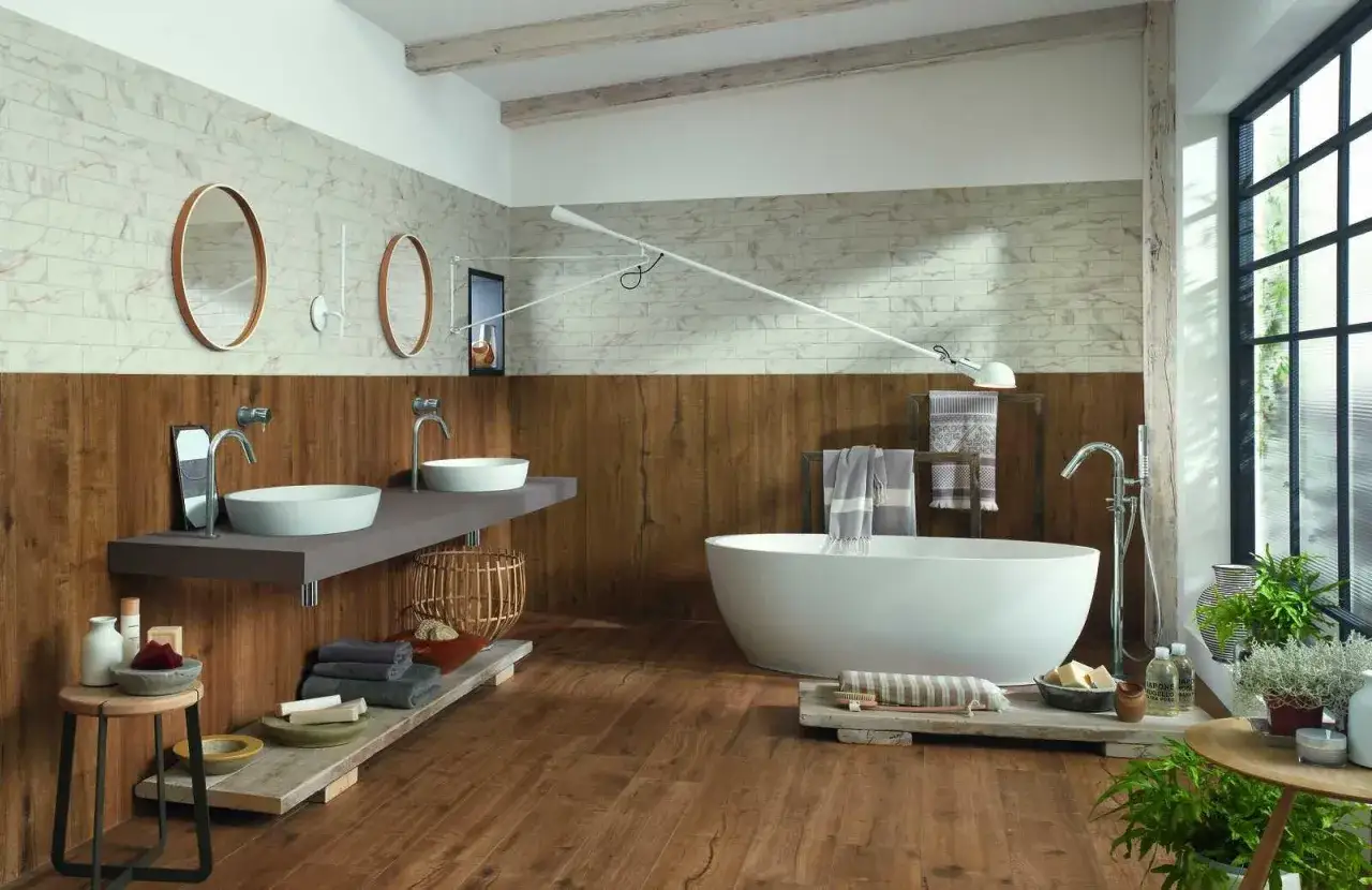 Salle de bain moderne avec pose carrelage imitation parquet au sol et murs en bois et marbre. Baignoire îlot, double vasque.