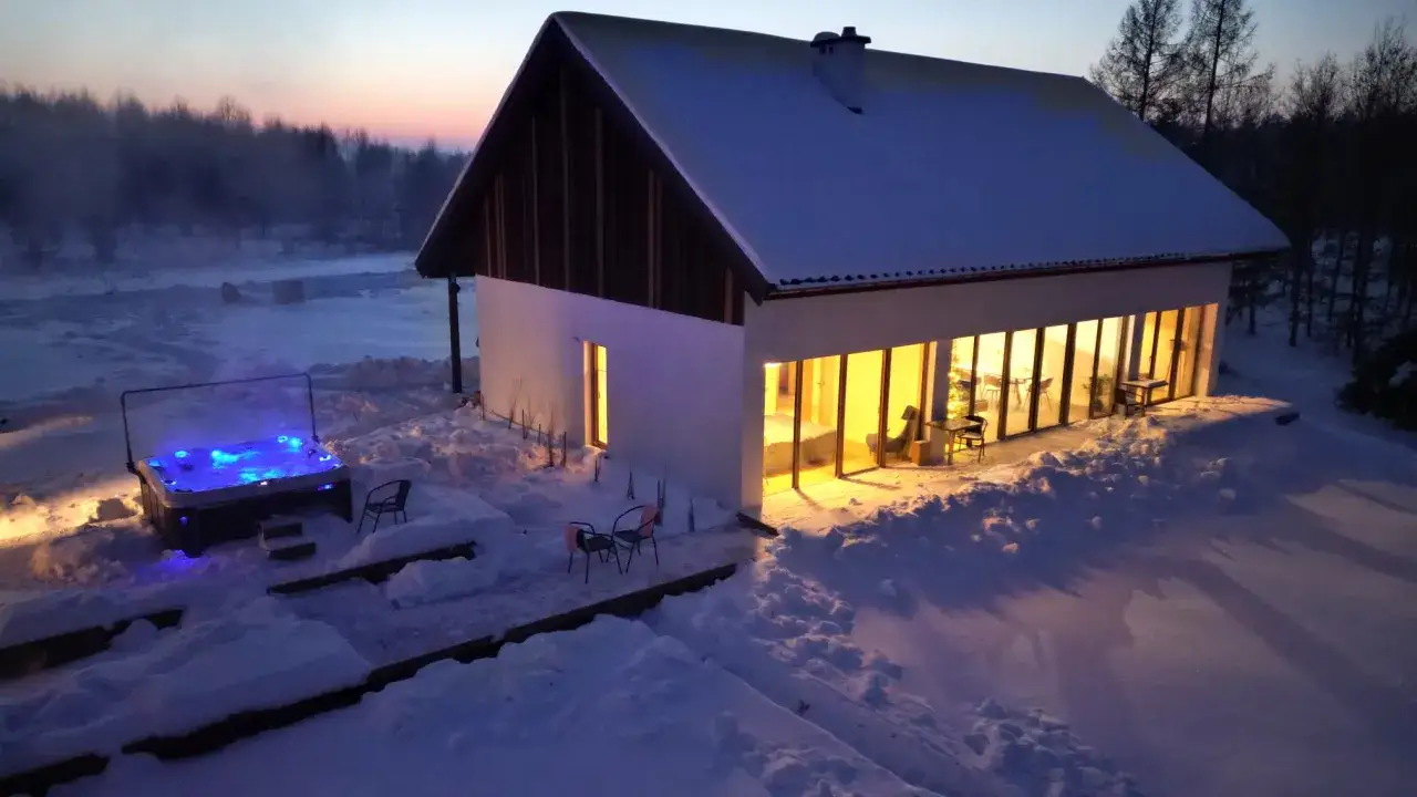 Zimowy wiecz&oacute;r, l.a.s. - lokum absolutnie spokojne. Rozświetlony, błękitny jacuzzi kusi ciepłem, podczas gdy dom emanuje przytulnym, ż&oacute;łtym blaskiem.