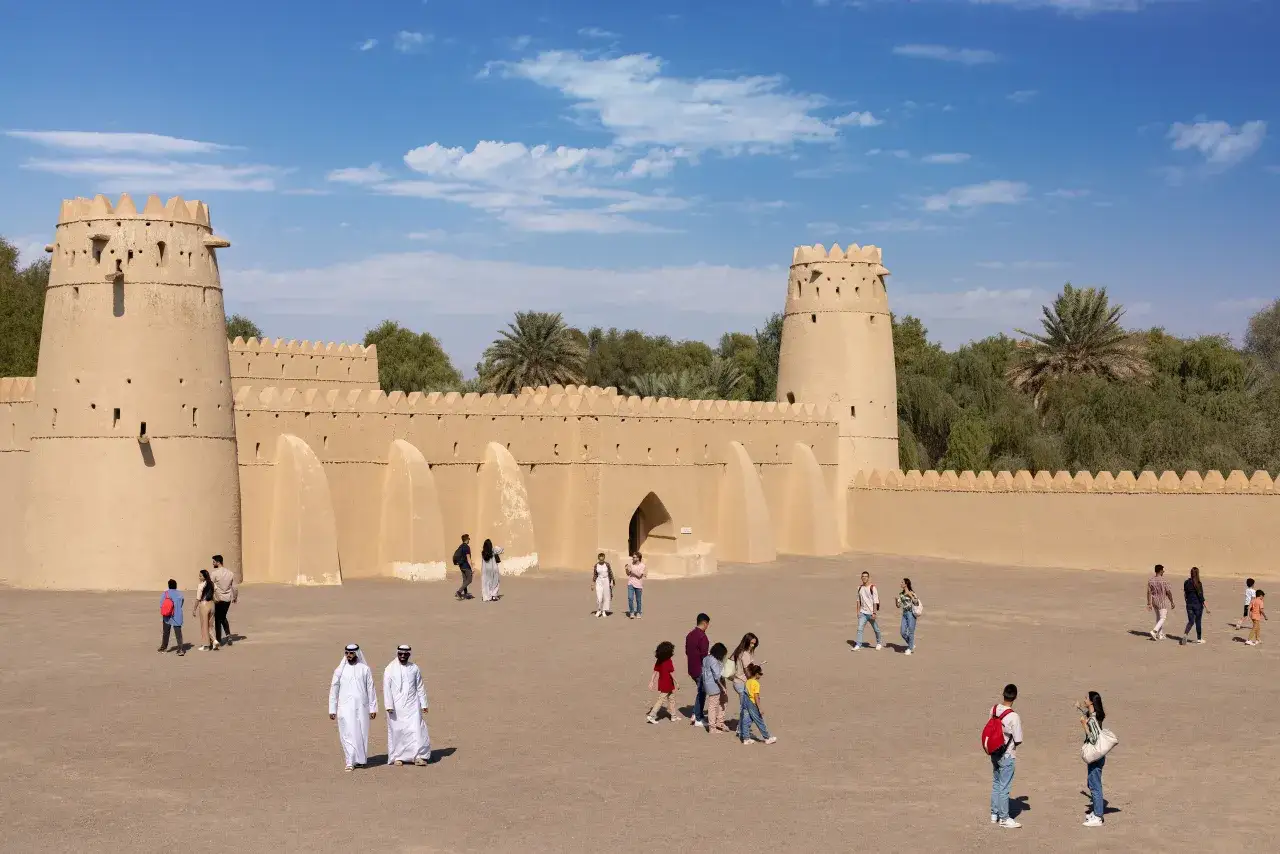 Ludzie zwiedzają zamek Jebel Hafeet Al Ain, tradycyjną budowlę z gliny pod błękitnym niebem.
