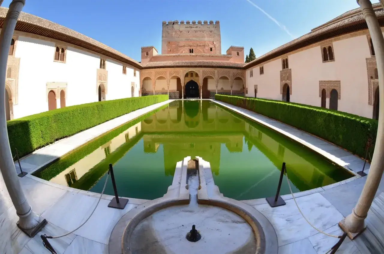 Der Patio der L&ouml;wen in der Alhambra mit seinem gr&uuml;nen Wasserbecken und der Festung im Hintergrund. Gute Erfahrungen beim Alhambra Tickets kaufen sind wichtig f&uuml;r diesen Anblick.