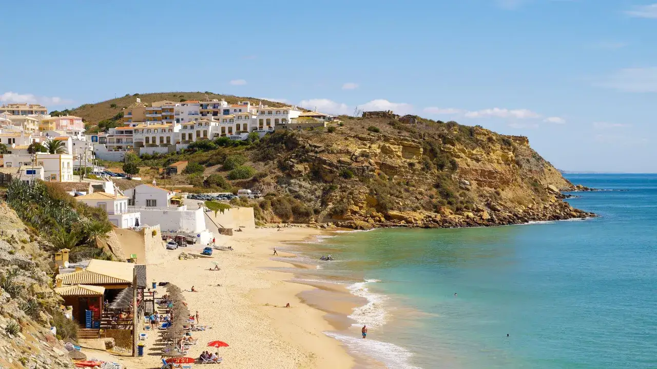 La **praia do Burgau** se despliega con arena dorada, aguas turquesas y casas blancas en la ladera. Un d&iacute;a perfecto para disfrutar del sol y el mar.