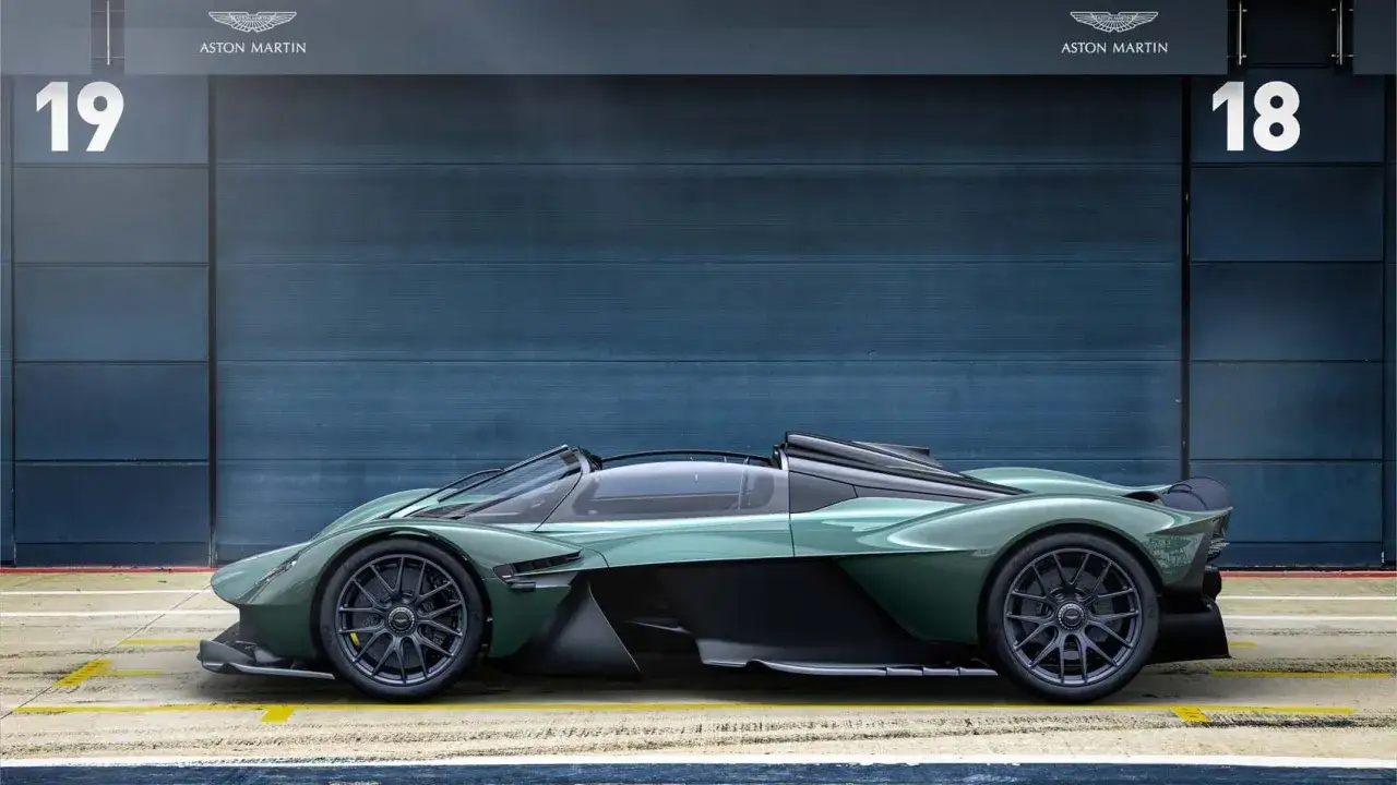 Grüner Aston Martin Valkyrie Spider mit offenem Verdeck steht vor einer blauen Wand mit den Zahlen 18 und 19.