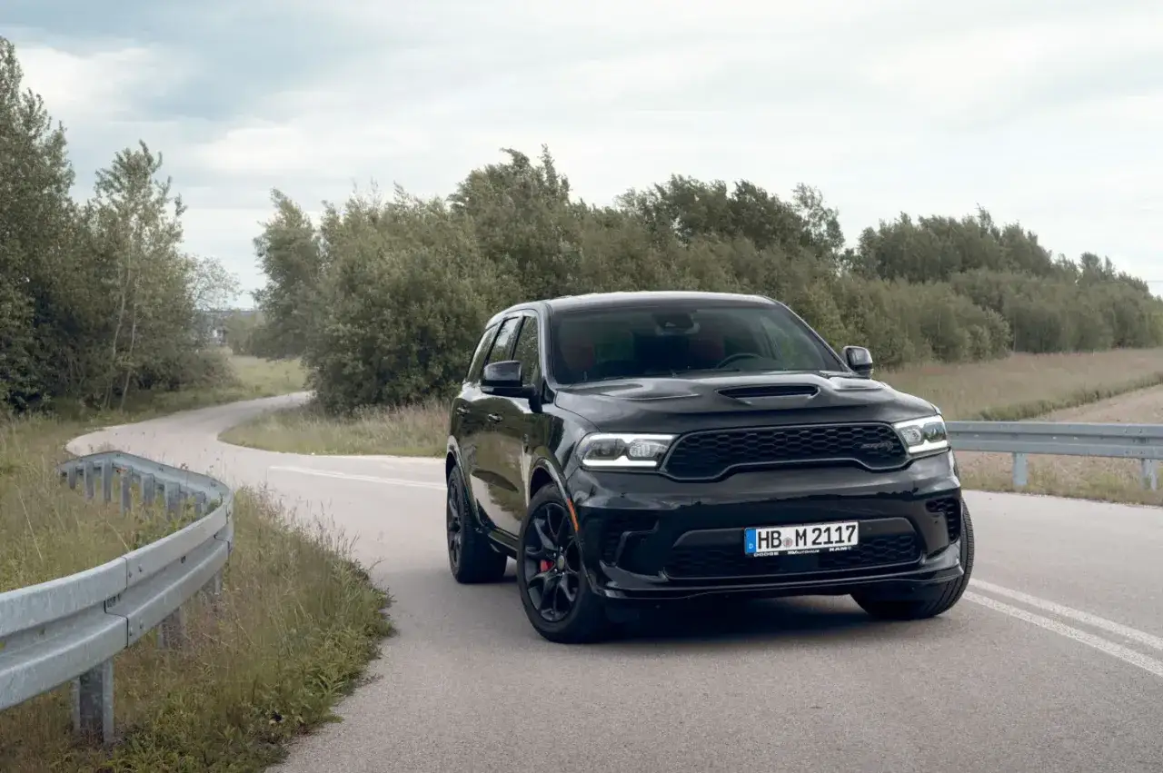Czarny Durango Hellcat na krętej drodze, otoczony zielenią.