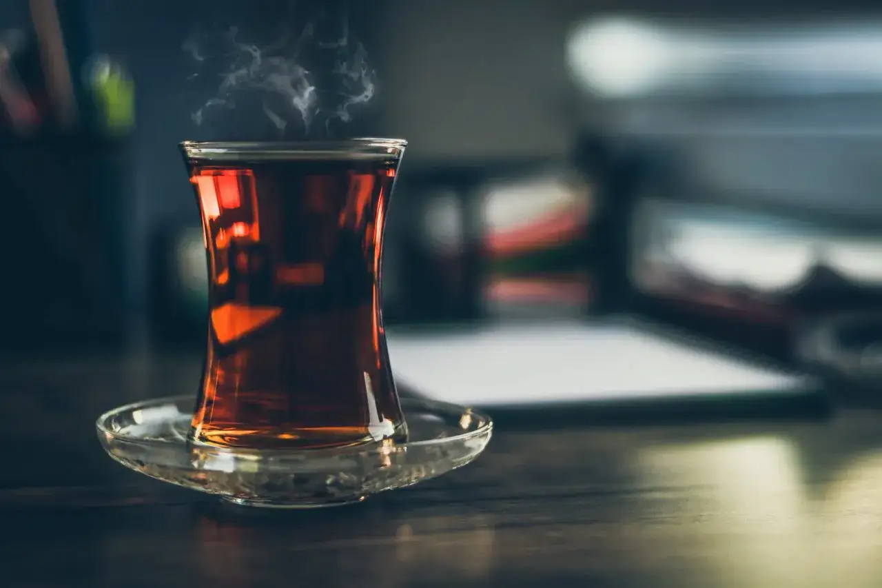 Un verre de thé noir fumant, une infusion réconfortante sur un bureau.