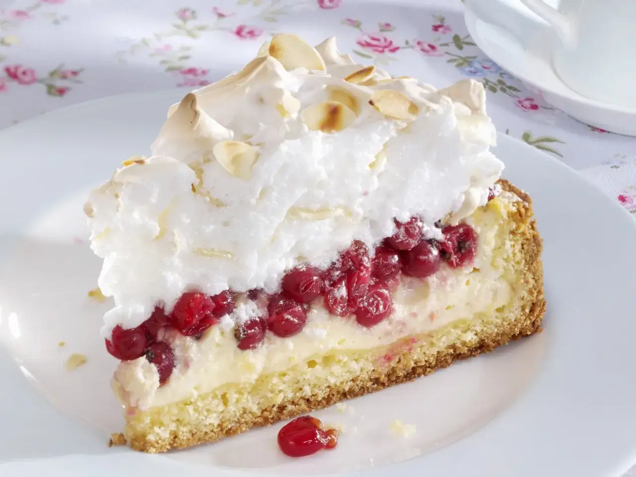 Ein St&uuml;ck Johannisbeer-Torte mit Baiserhaube und Mandelsplittern. Ein k&ouml;stliches Rezept f&uuml;r den Sommer.