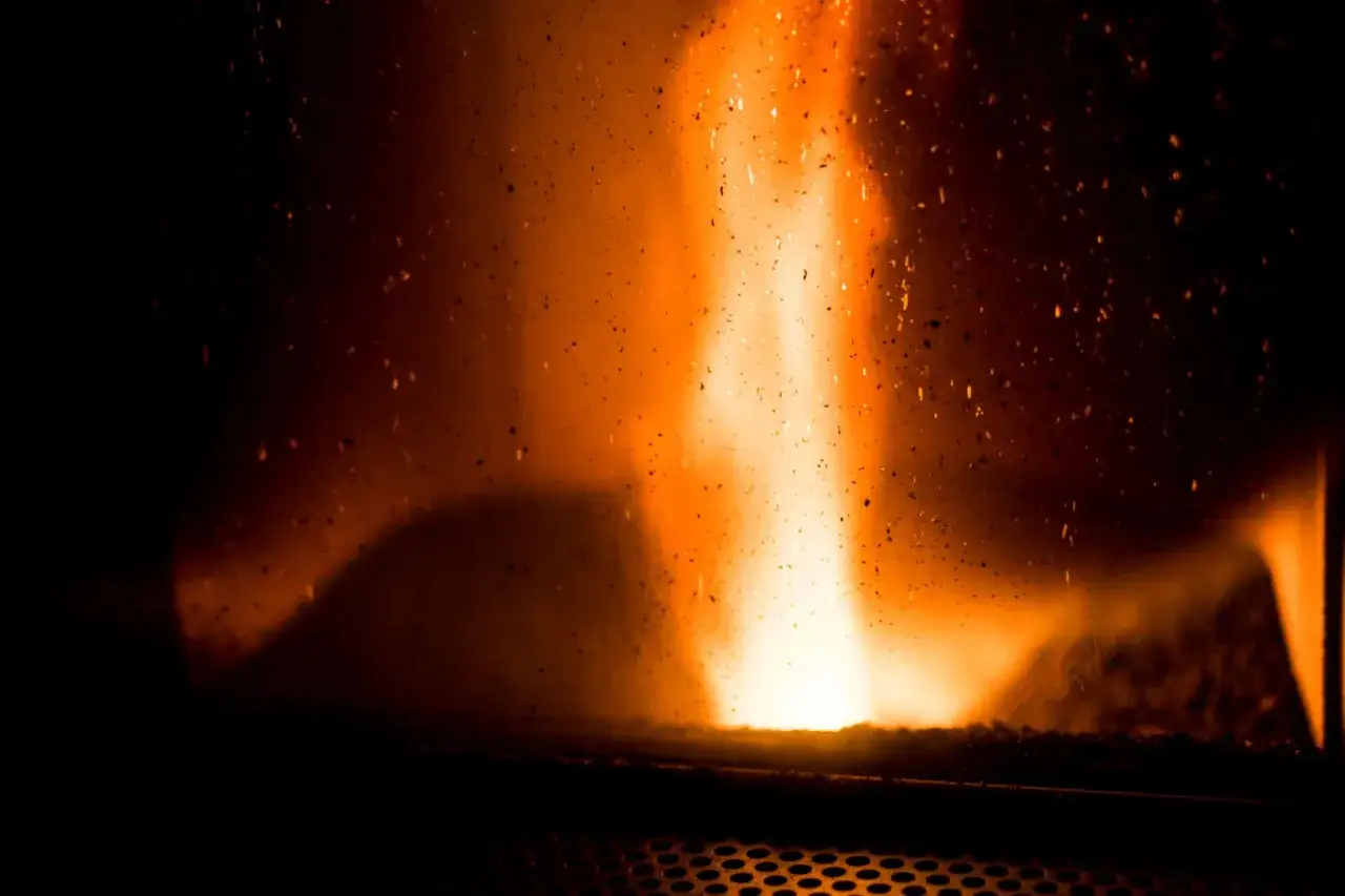 Flammes dansantes &agrave; travers la vitre noire d'un po&ecirc;le &agrave; granul&eacute;s. Les r&eacute;glages parfaits pour une chaleur r&eacute;confortante.