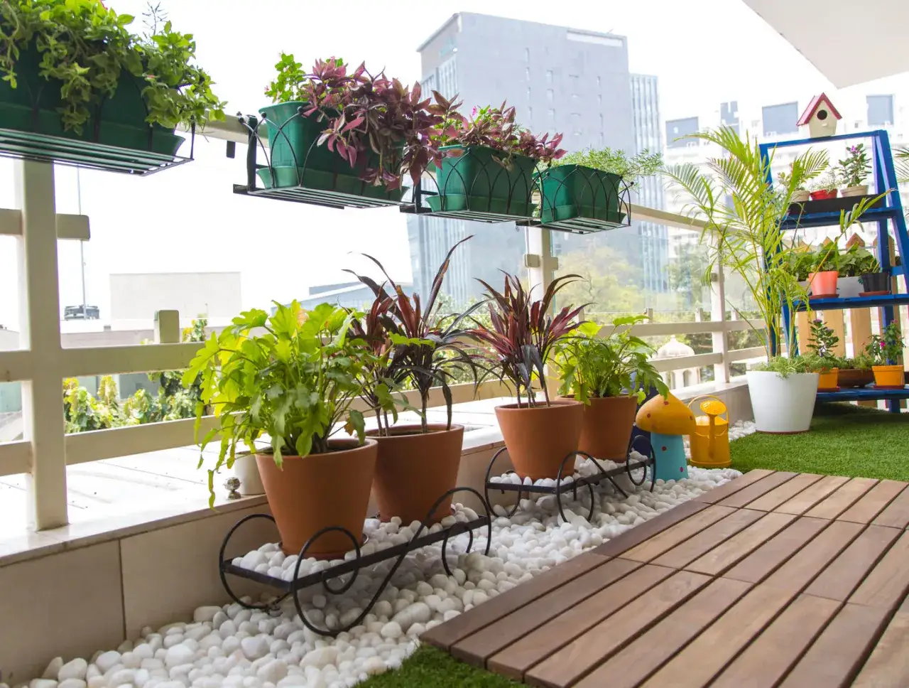 Ideas para decorar terrazas barato: plantas en macetas de terracota y estanterías azules con vegetación crean un oasis urbano.