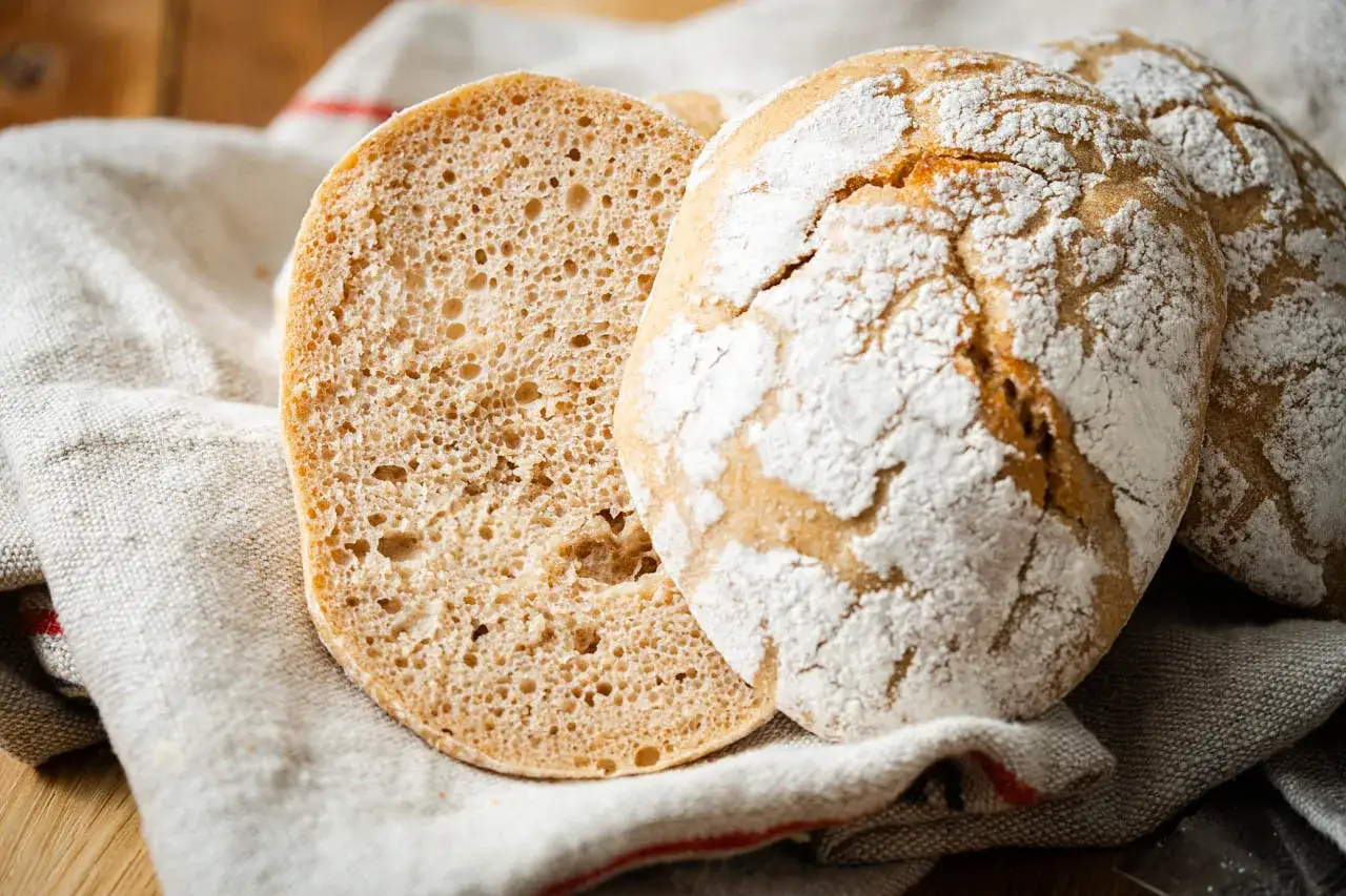 Frisches Brot, eines aufgeschnitten, zeigt eine luftige Krume. Perfekt für alle, die keine discard rezepte mögen.