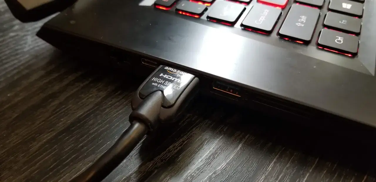 Ein HDMI-Kabel wird in einen Laptop gesteckt, um den **pc mit fernseher verbinden** zu können.