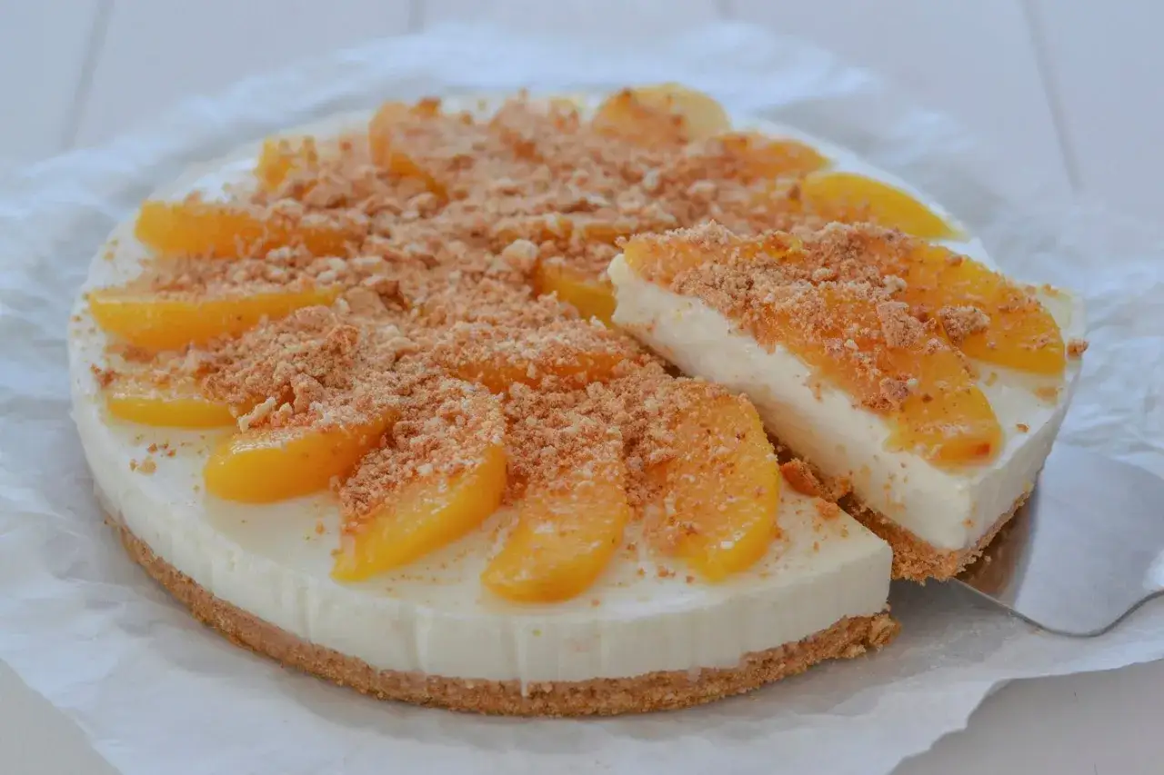 Torta pesche e amaretti: una delizia cremosa con pesche sciroppate e crumble croccante. Una fetta &egrave; gi&agrave; stata servita.