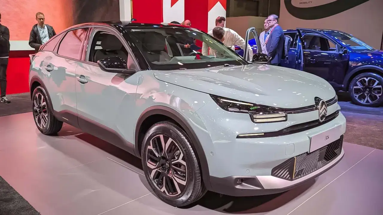 En ljusgrå Citroën C4, redo för ett citroen c4 test, visas upp på en mässa med besökare som tittar.