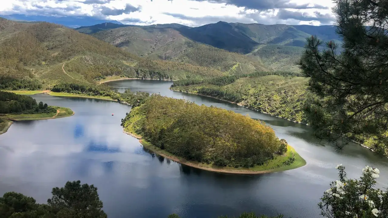 Idyllische Seenlandschaft in Extremadura, Spanien, mit bewaldeten H&uuml;geln und einem ruhigen Gew&auml;sser.