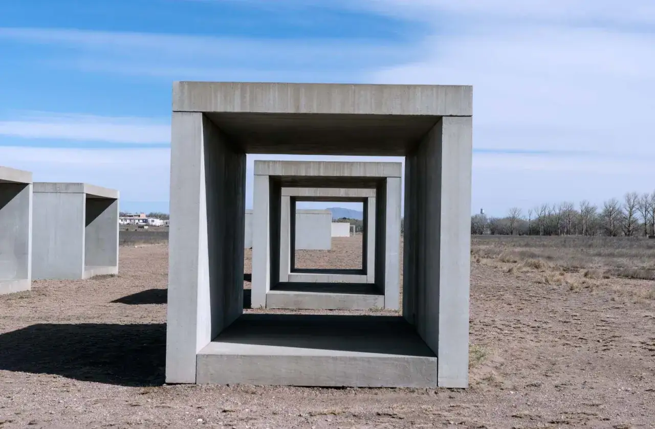 Concrete cubes recede into the distance, a minimalist landscape of Donald Judd art under a vast blue sky.