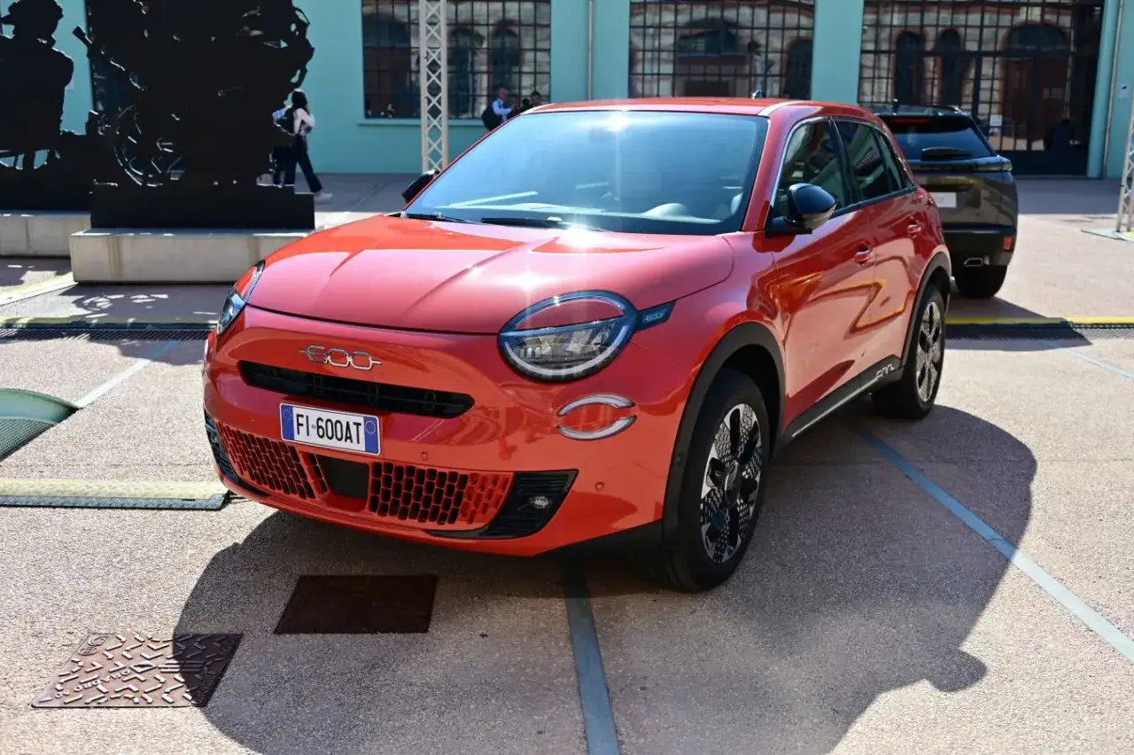Nowy Fiat 600, kompaktowy SUV, prezentuje swoje wymiary na tle industrialnej architektury.