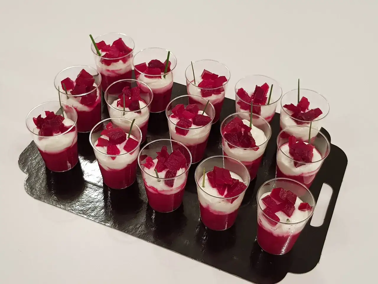 Douze verrines de mousse de betterave et crème, garnies de dés de betterave et d'une tige de ciboulette.