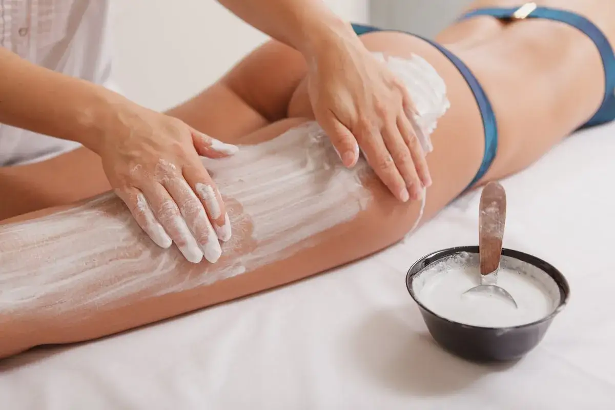 Applicazione di fanghi anticellulite sulle gambe. Per risultati ottimali, chiedi al tuo estetista quante volte a settimana è consigliato il trattamento.