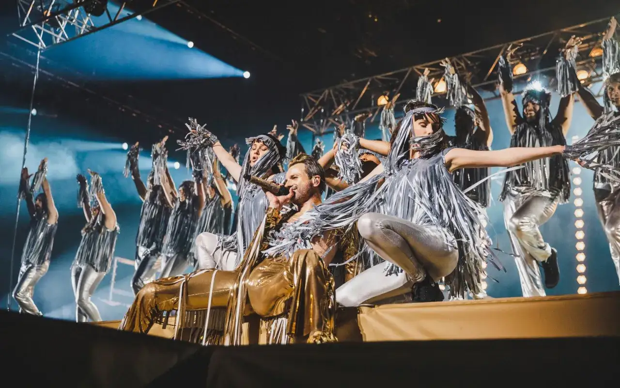 Jesus Christ Superstar i Stockholm: en gyllene artist sjunger medan dansare i silvergl&auml;nsande dr&auml;kter lyfter sina armar.